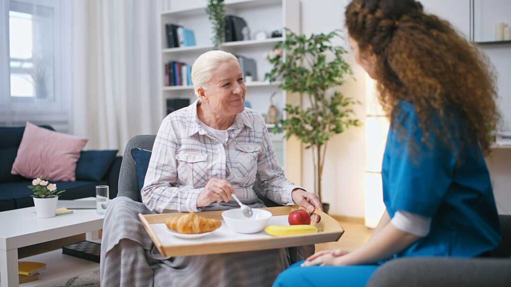 An older adult and family member packing boxes together in a cozy, furnished living room.
