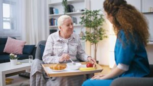 An older adult and family member packing boxes together in a cozy, furnished living room.